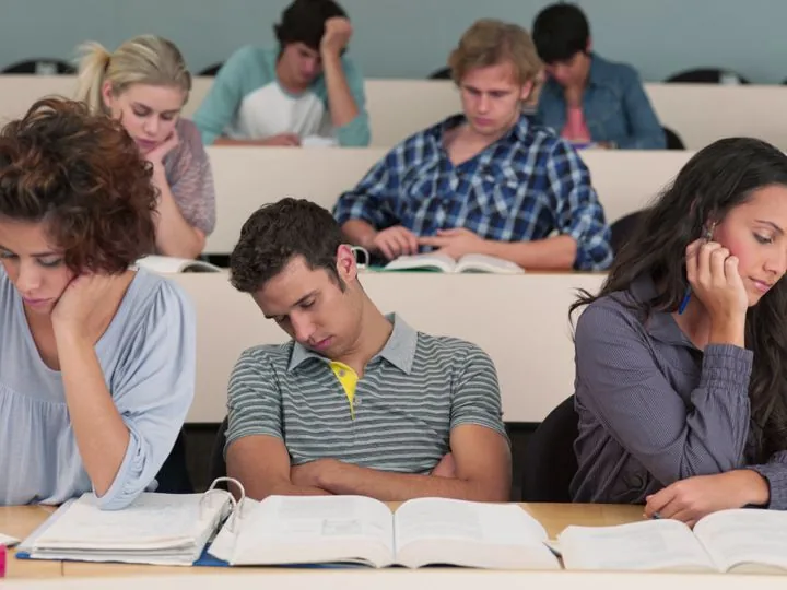 Bored students falling asleep over their books in a lecture hall