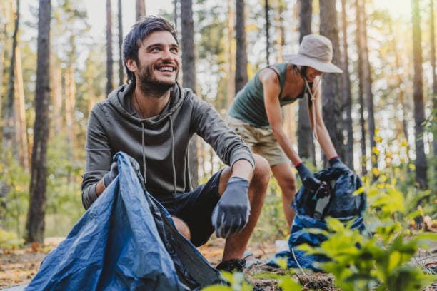 Two volunteers picking up litter in a forest